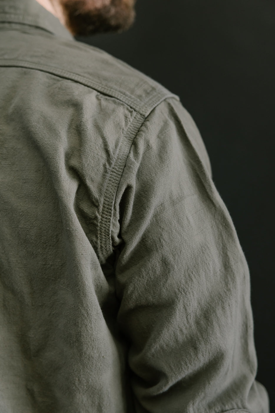 Close-up of the SSS25-ATW Tropical Weather Dobby Shirt in olive green, highlighting the textured dobby weave and precise stitching on the shoulder area.