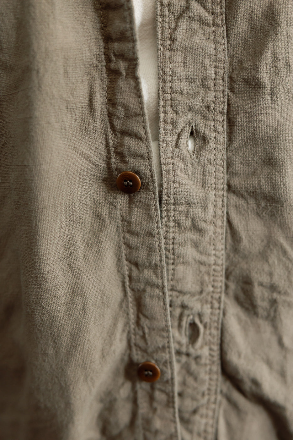 Close-up front view of men's shirt showing button placket, brown buttons, and textured fabric detail.