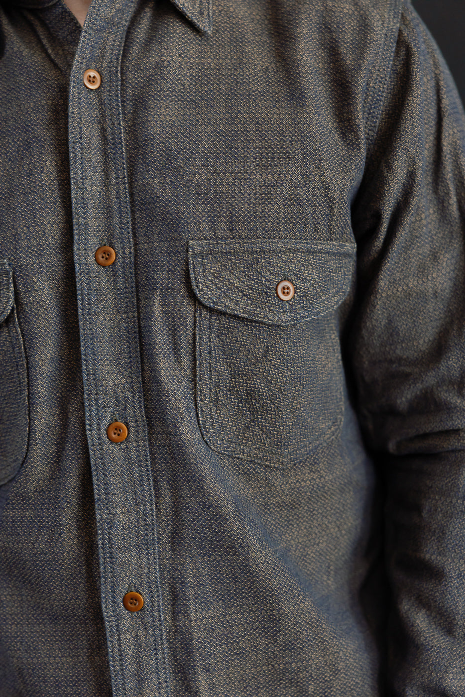 Close-up front view of men's denim shirt with chest pocket, button details, and textured fabric