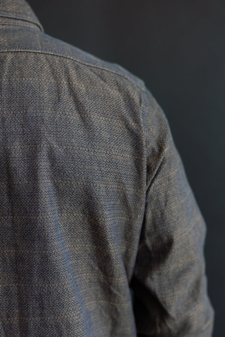 Close-up of male model's shoulder, showcasing denim shirt texture and stitching detail.