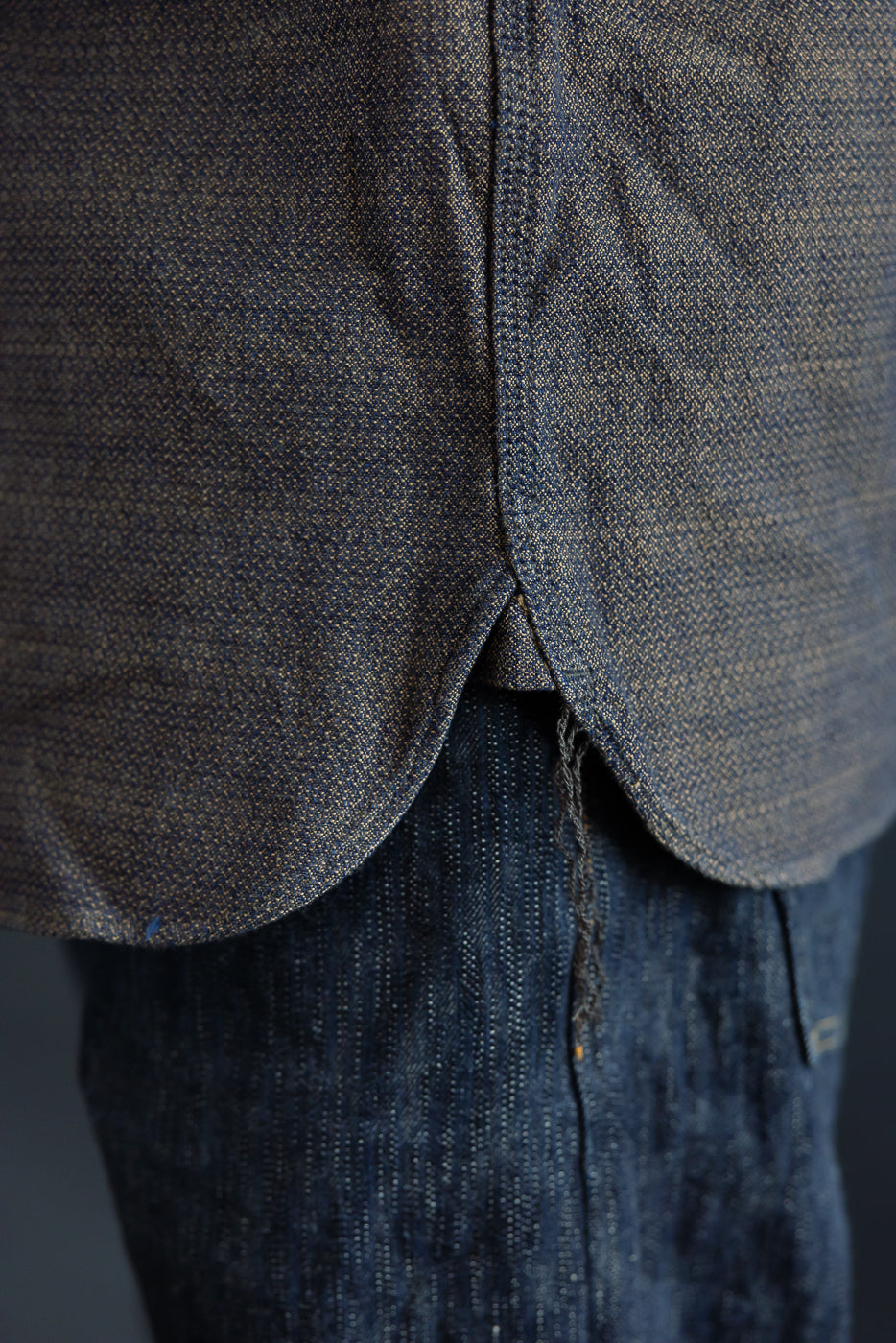 Close-up of shirt hem and denim texture, front view, worn by male model
