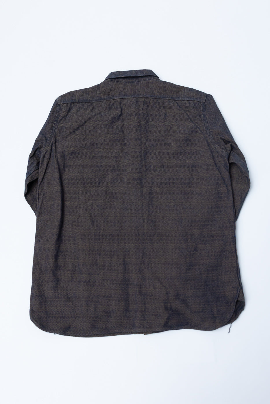 Back view of dark selvedge shirt, flat lay, showcasing fabric texture and hem detail