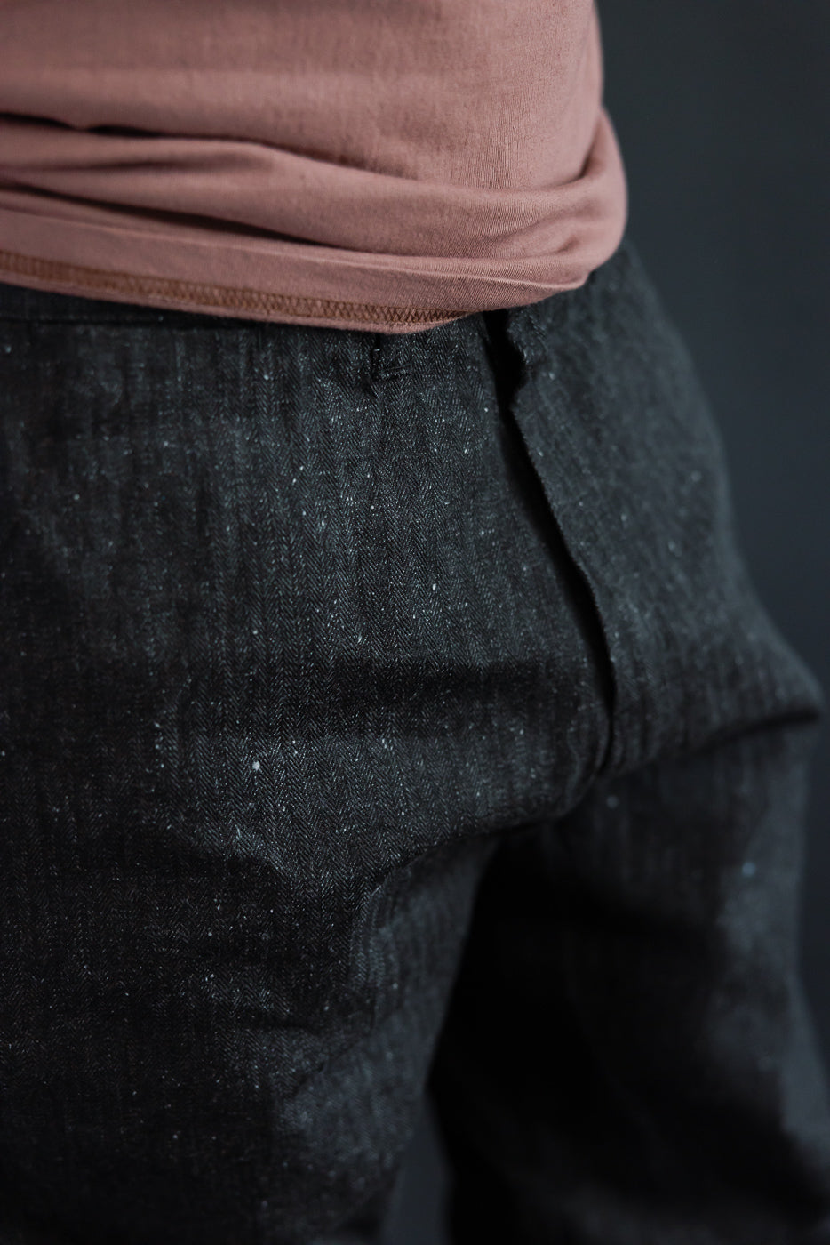 Close-up front view of dark selvedge denim pants with herringbone texture, worn by male model, 5'9