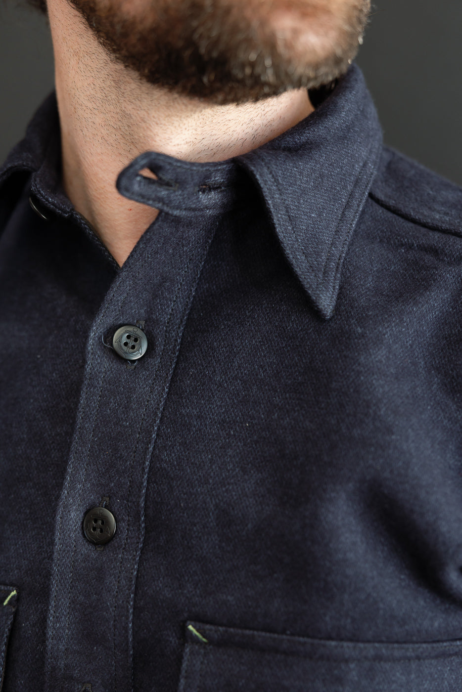 Close-up front view of dark denim shirt on male model, 5'9