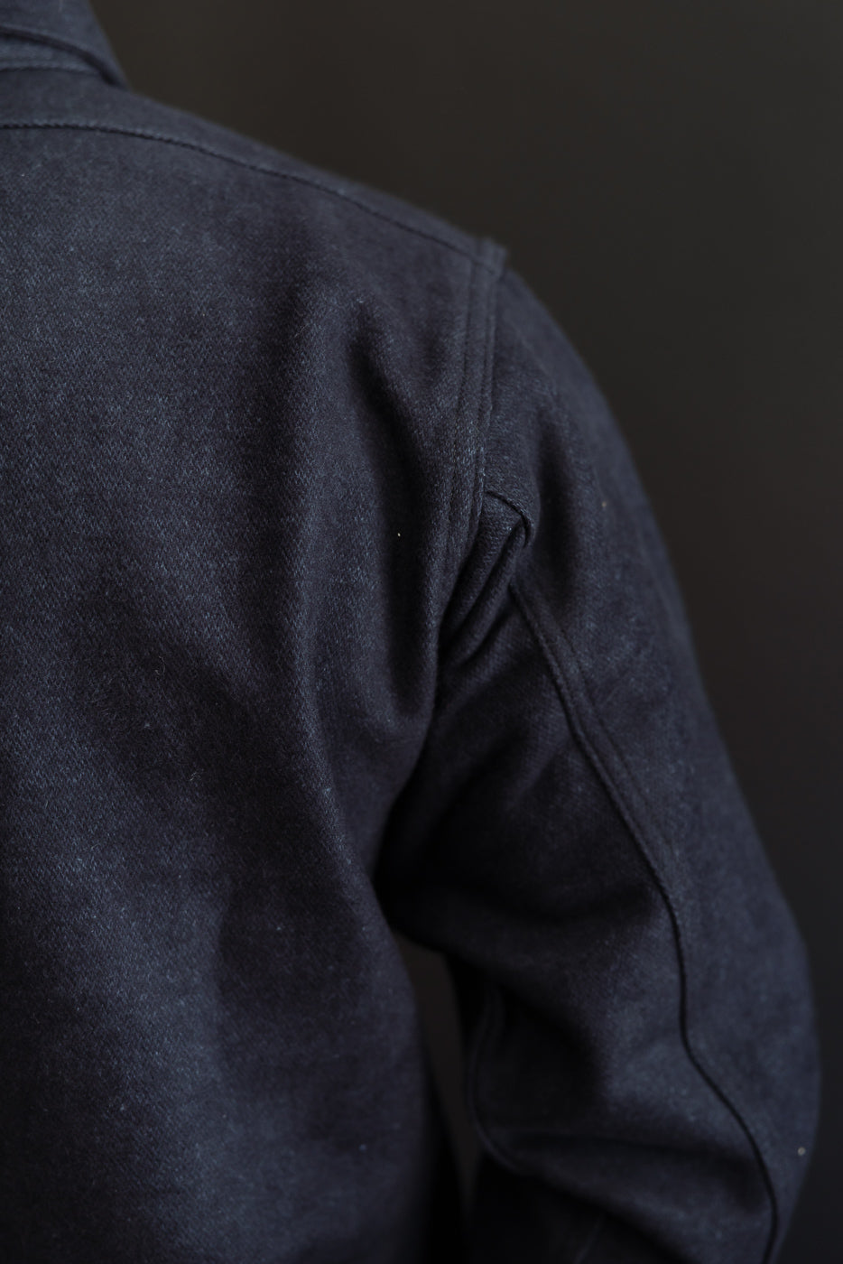Close-up back view of dark denim shirt on male model, 5'9