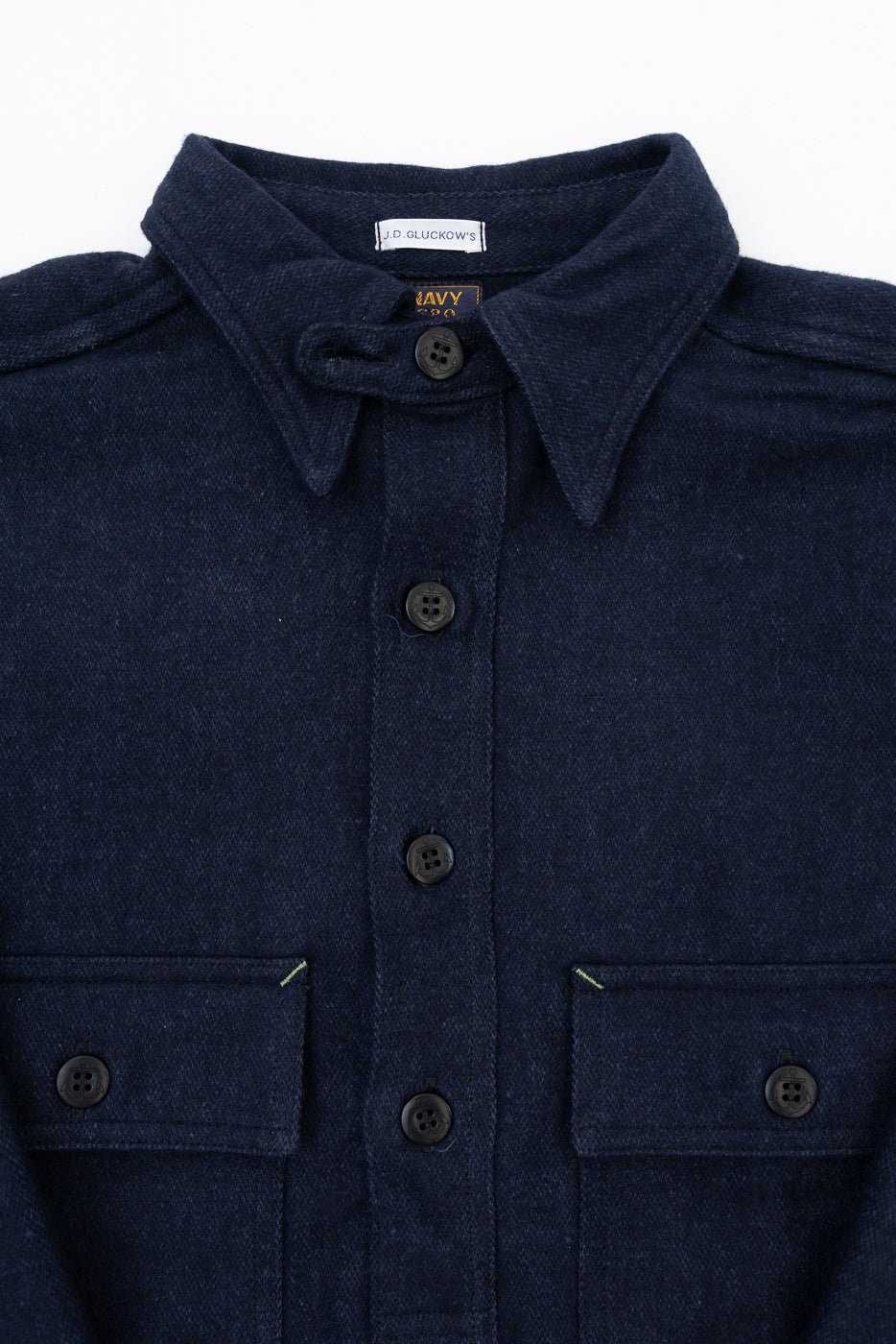 Close-up front view of navy shirt: button-down collar, chest pockets, dark buttons, J.D. Gluckow's tag