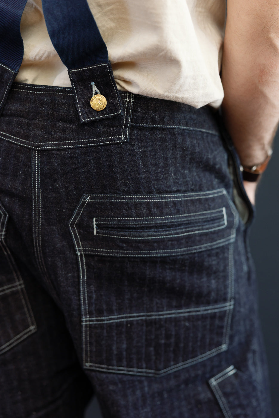 Close-up rear view of dark selvedge denim overalls on male model, 5'9
