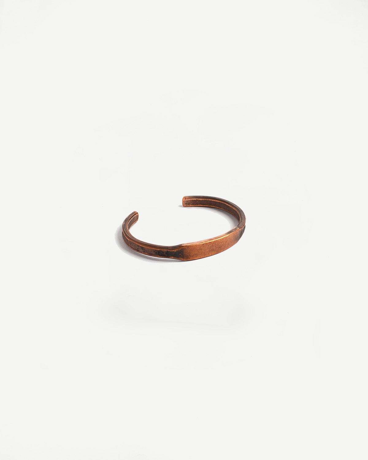Close-up of Studebaker copper ID cuff bracelet with patina finish on white background.