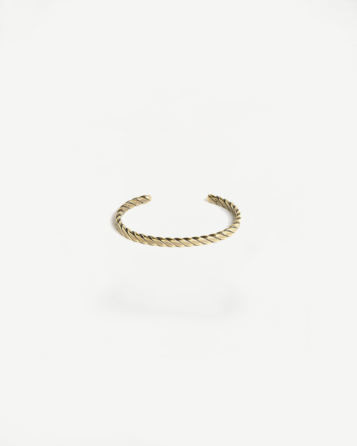 Close-up of brass plait cuff bracelet with patina, accessory flat lay, front view on white background