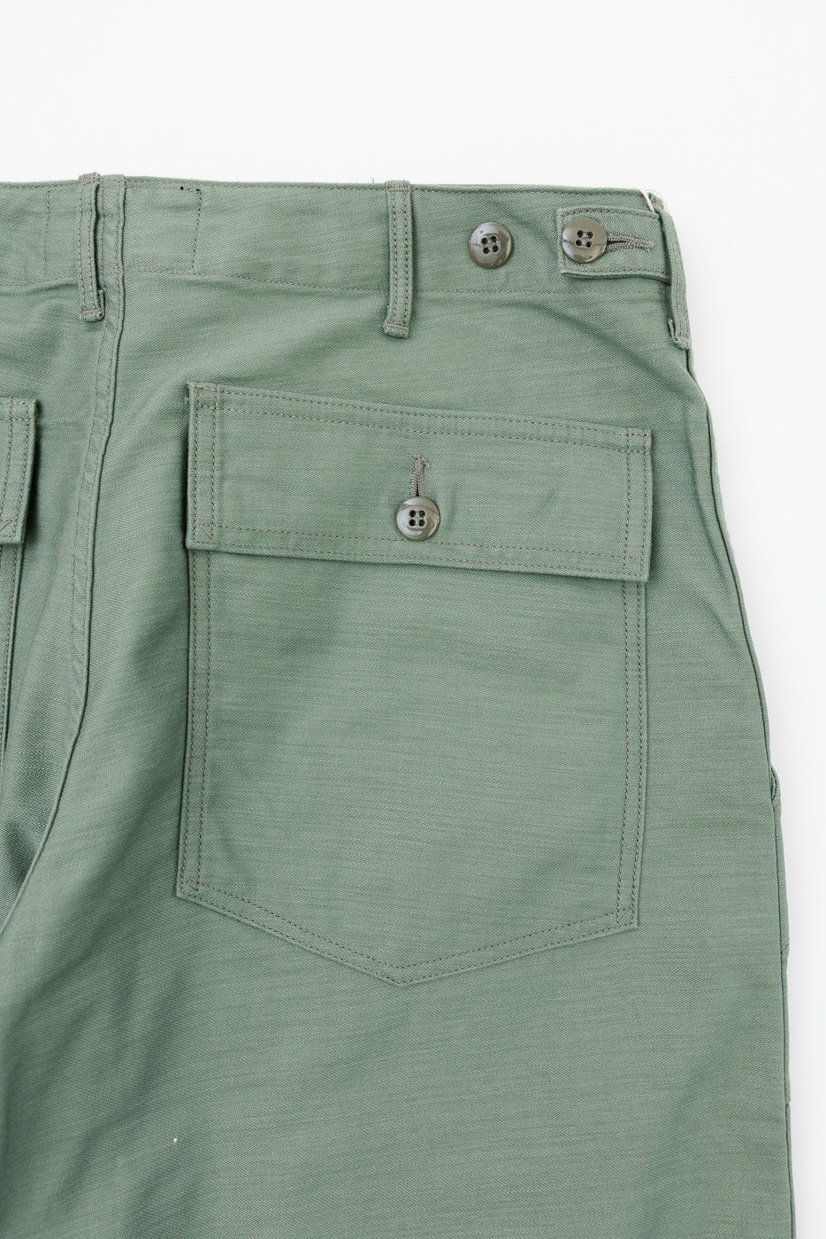 Close-up front view of sage green casual pants with button-flap pocket, belt loops, and metal buttons
