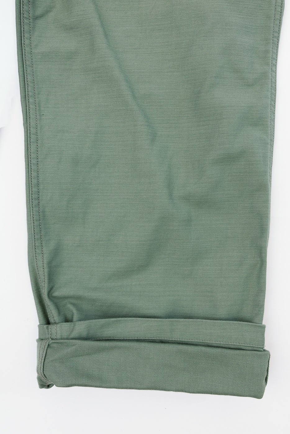 Close-up front view of olive green casual pants, cuffed hem, visible stitching, fabric texture