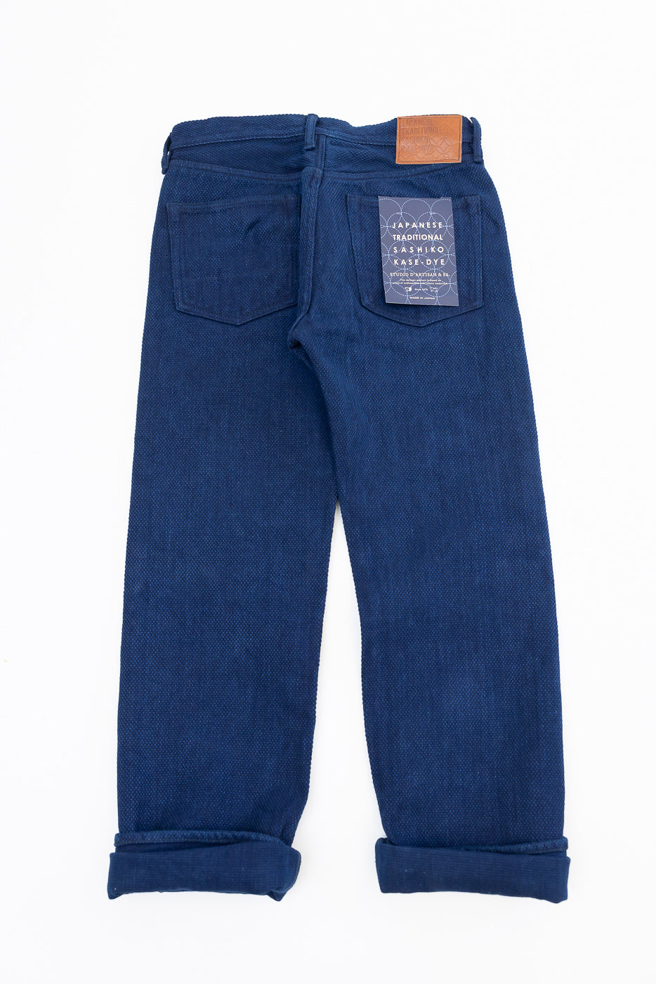 Back view of indigo selvedge jeans with rolled hems, leather patch, and tag detail