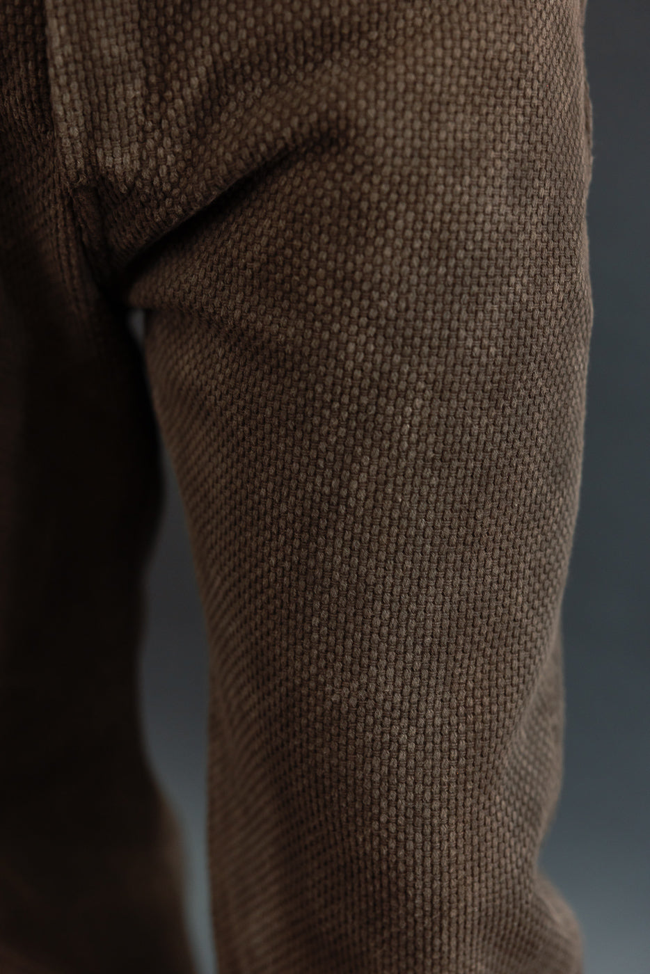 Close-up of brown textured knit pants leg, showing fabric weave detail on male model