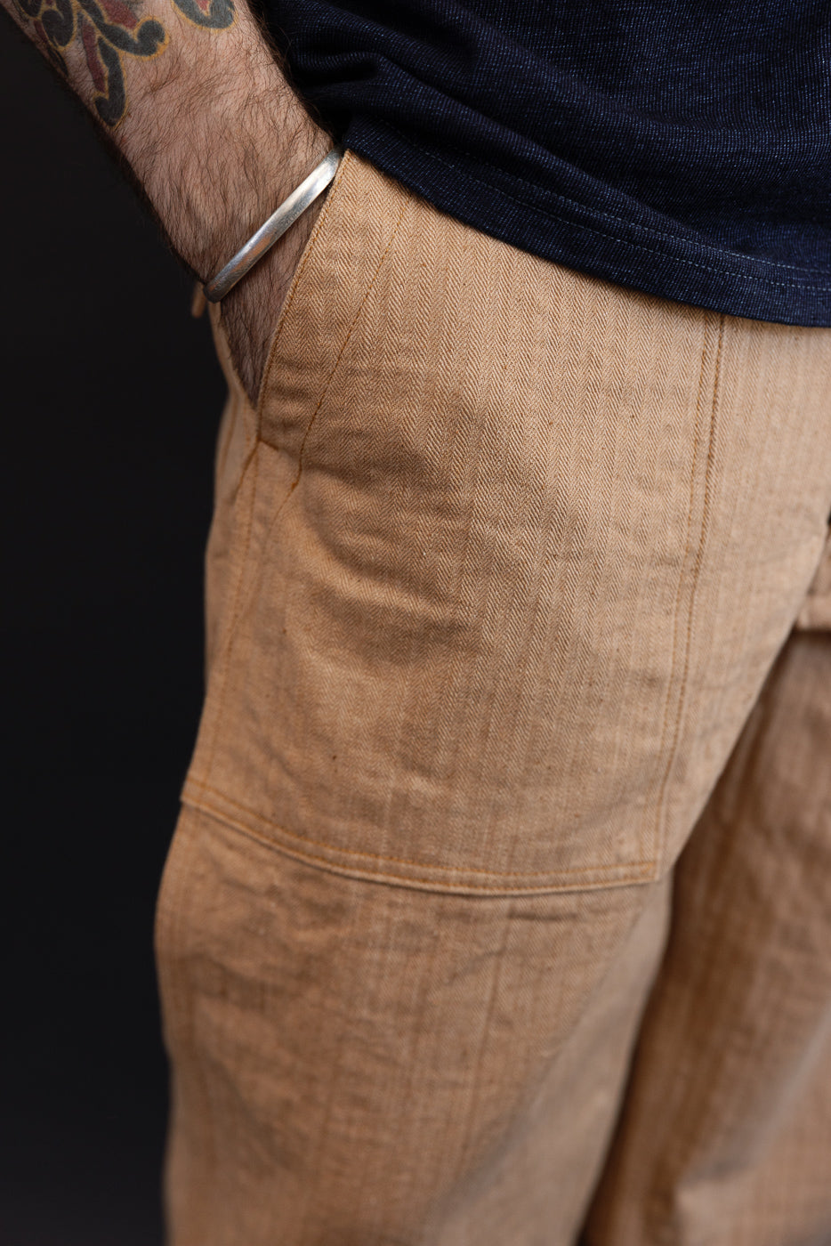 Close-up side view of tan herringbone linen pants on male model, 5'9