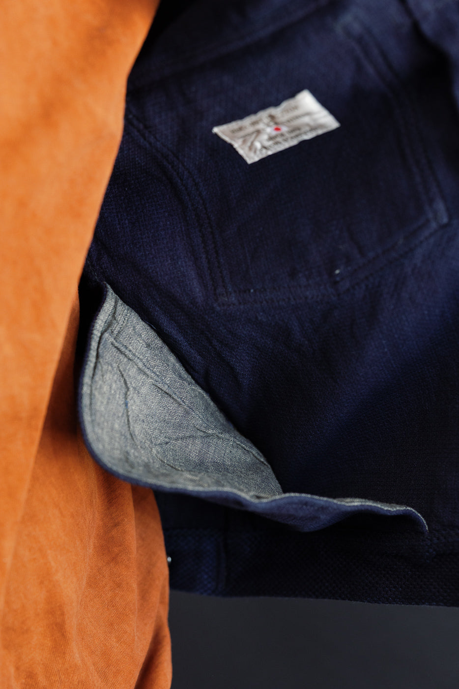 Close-up of navy selvedge denim jacket's inner lining and tag, showing texture and craftsmanship details.