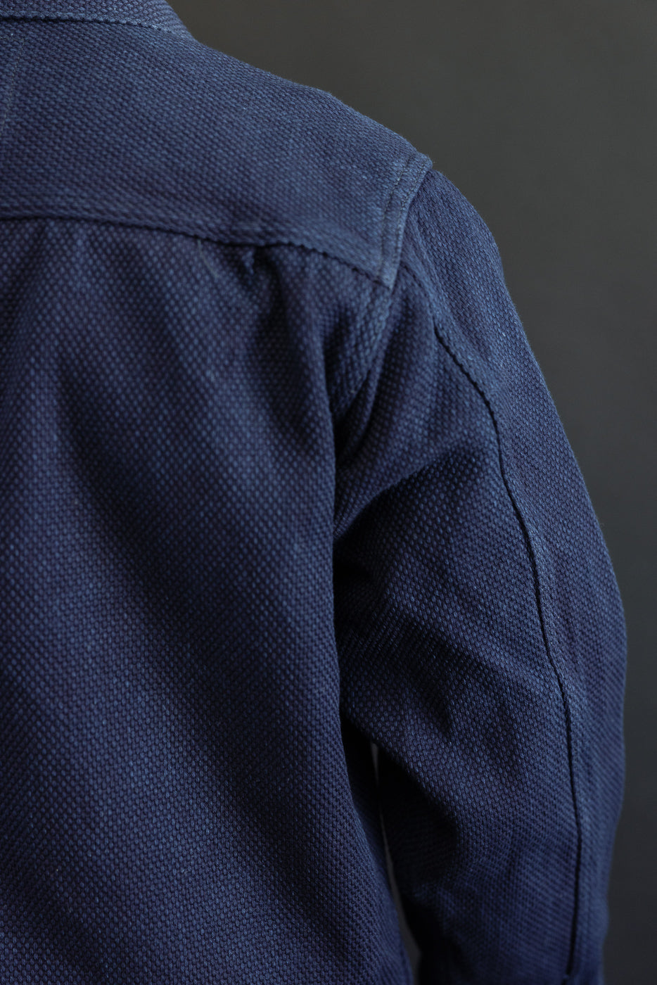 Close-up of navy shirt shoulder, showing fabric texture and stitching detail