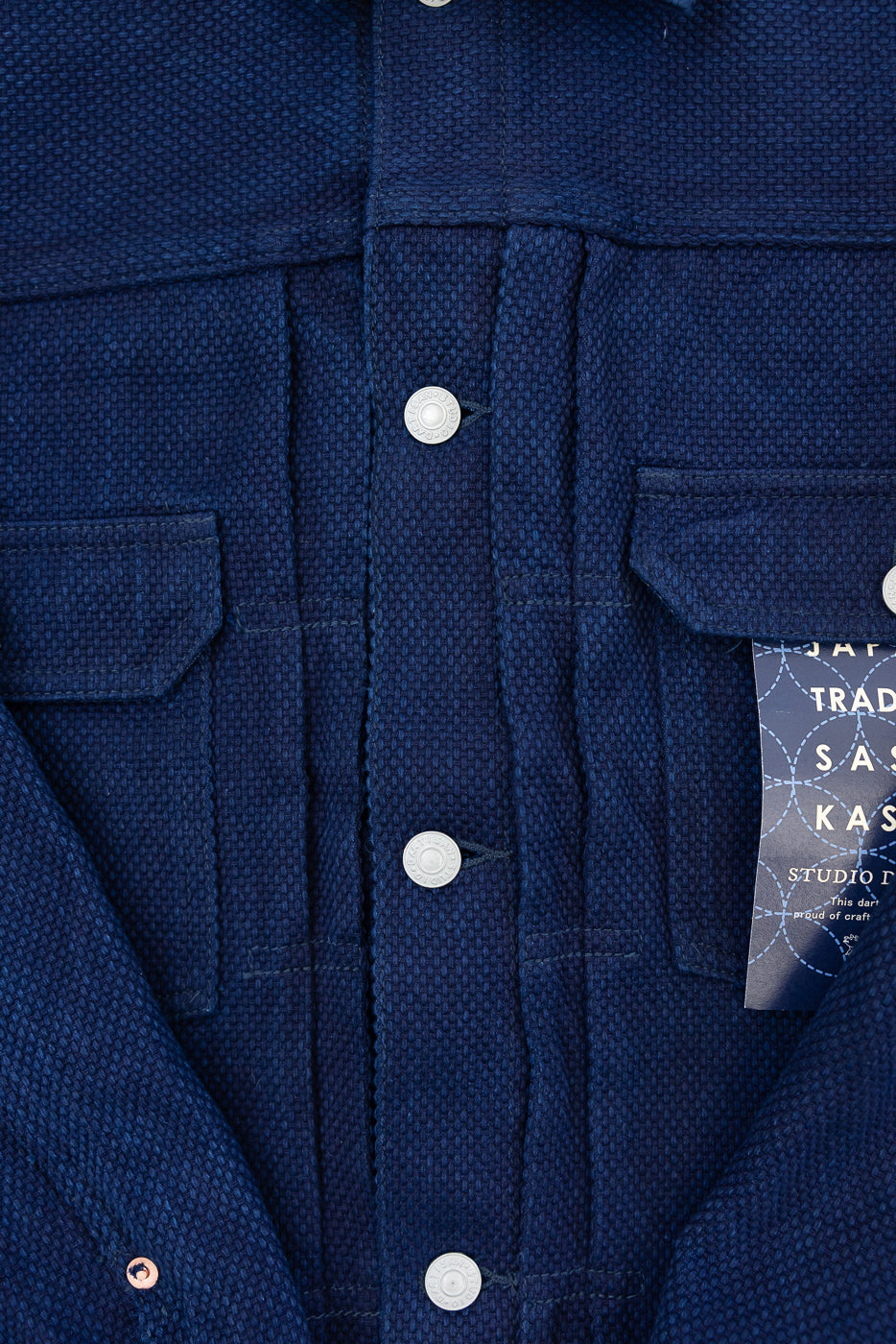 Close-up front view of navy blue shirt with textured fabric, silver buttons, and chest pockets