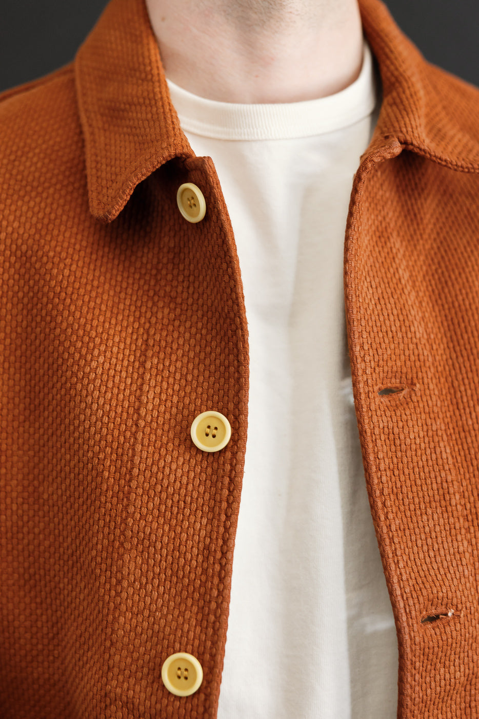 Close-up front view of a male model wearing a rust corduroy shirt with visible fabric texture and buttons.