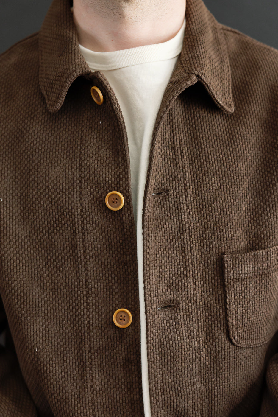 Close-up front view of a brown textured jacket with buttons on a male model, 5'9