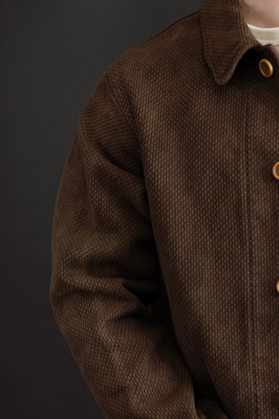 Close-up of the front of a brown corduroy shirt showing the collar and buttons.