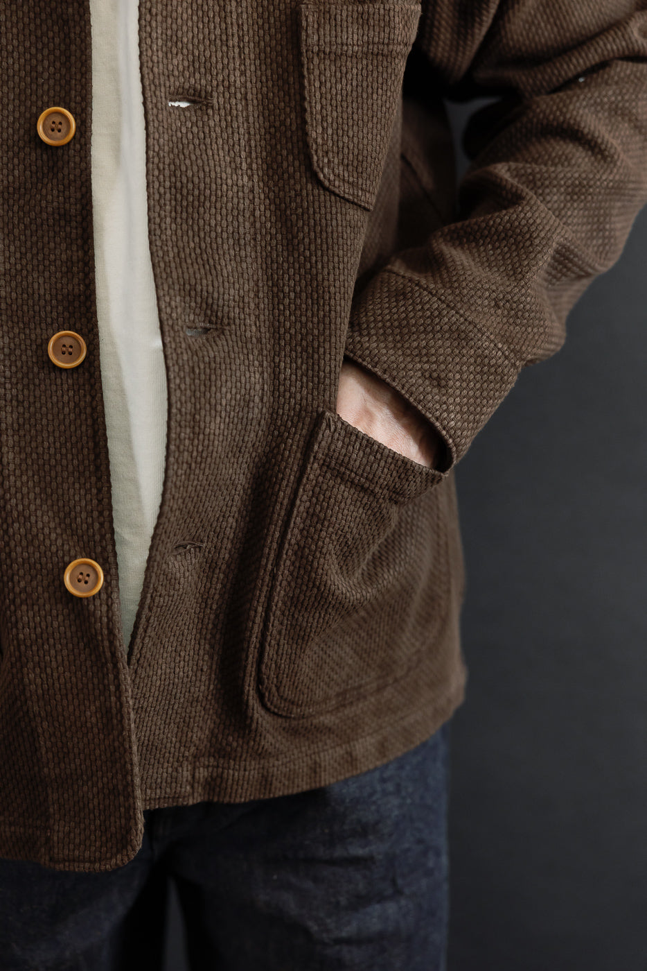 Close-up front view of a male model wearing a brown corduroy jacket with visible texture and buttons.