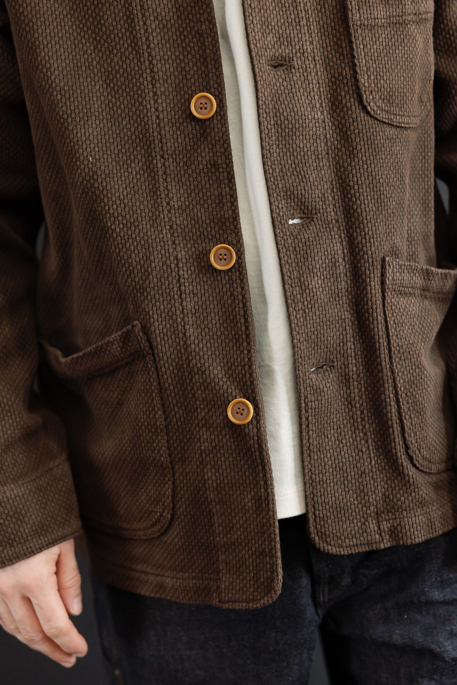 Close-up front view of a brown corduroy jacket showing button details and fabric texture.