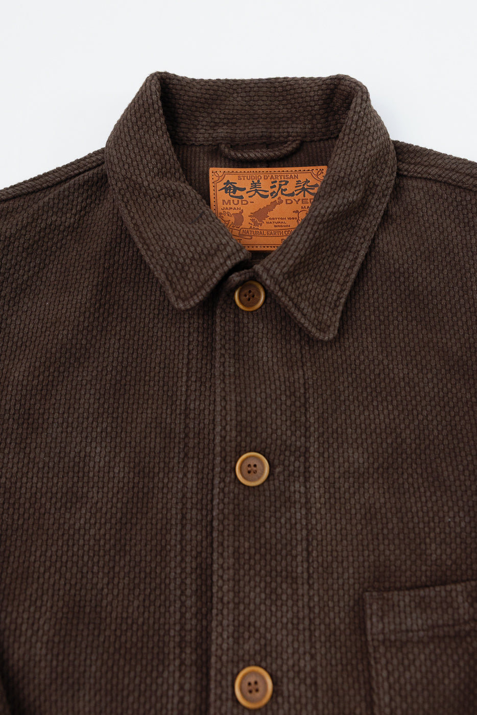Close-up of the front collar and placket of a brown textured jacket with a leather tag.