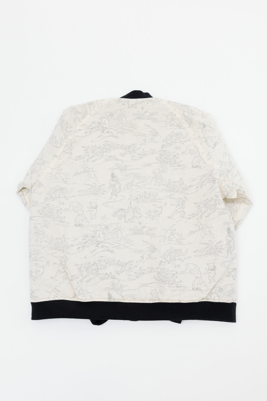 Back view flat lay of cream bomber jacket with grey storybook print, black ribbed hem and collar