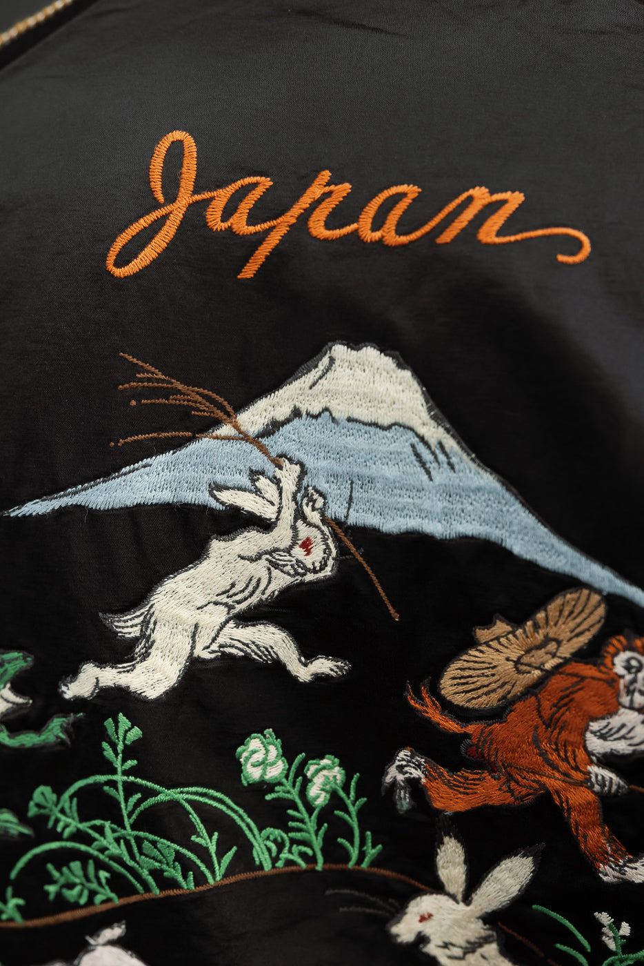 Close-up of black jacket back with 'Japan' embroidery, Mt. Fuji, rabbits, and monkey design