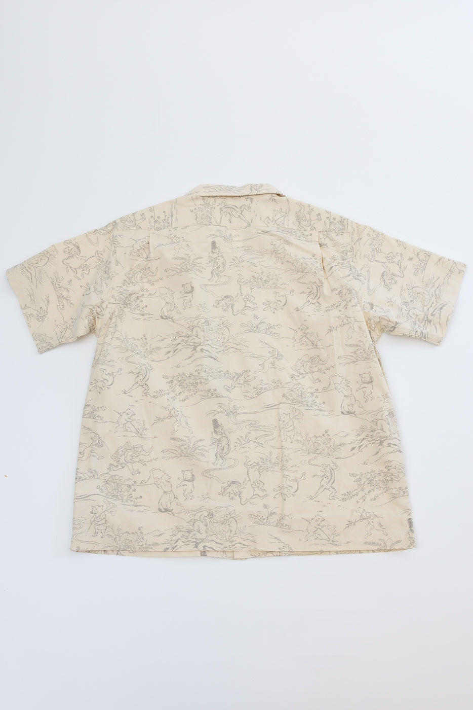 Back view of beige short-sleeve shirt with intricate gray pattern, flat lay