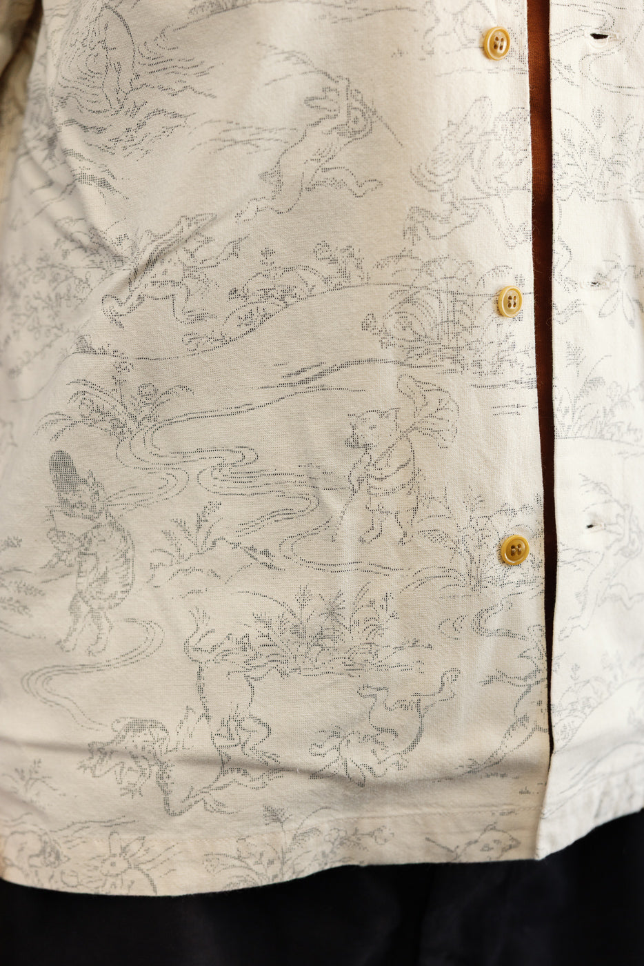 Close-up front view of men's patterned button-up shirt with nature print, yellow buttons, and fabric texture detail