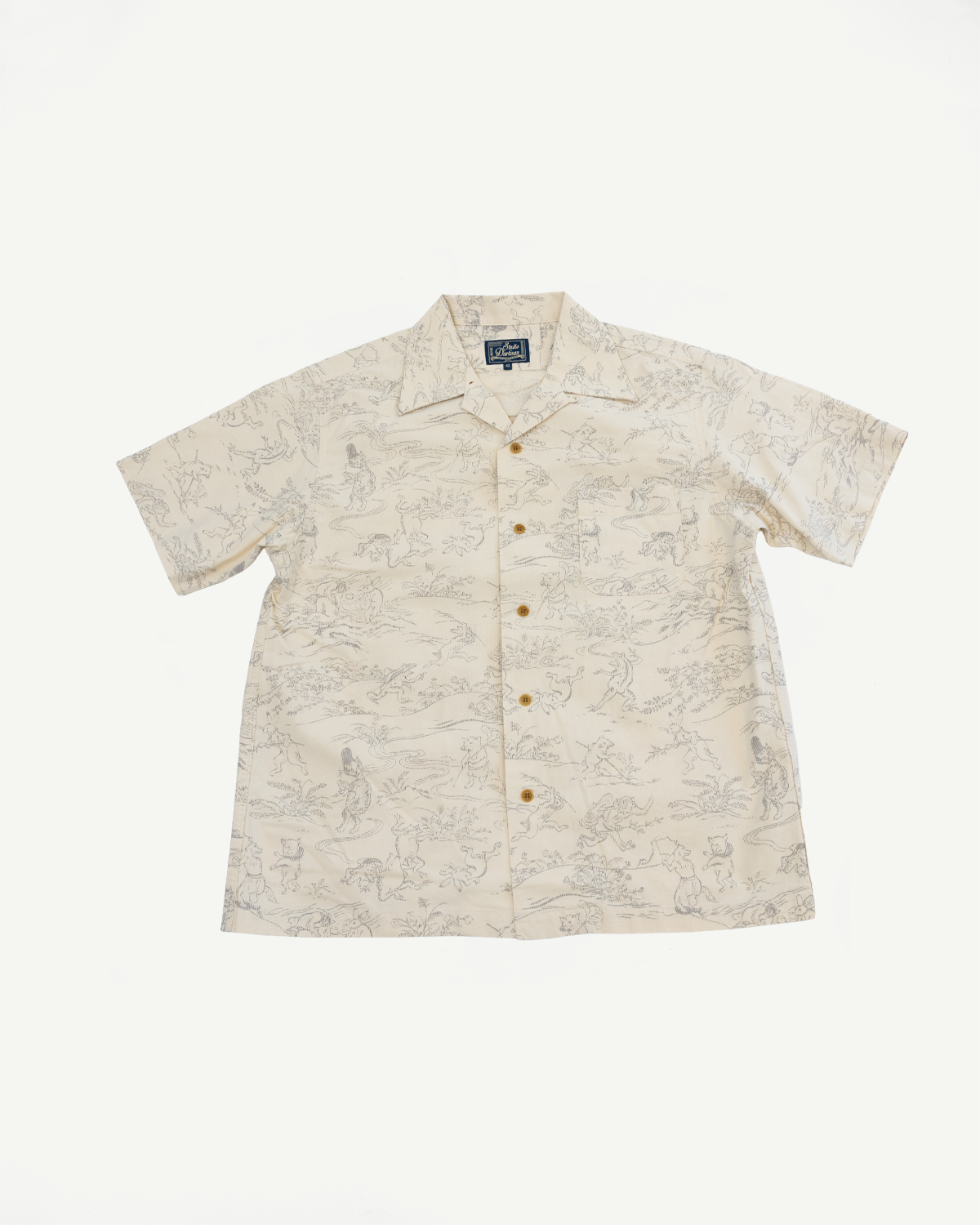 Front flat lay of cream short-sleeve shirt with animal print, button closure, and collar detail.
