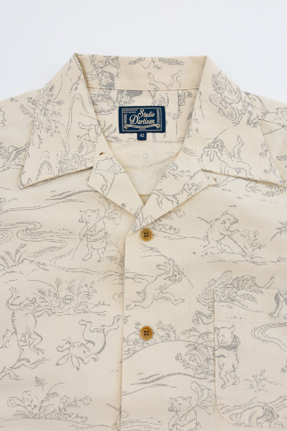 Close-up front view of cream shirt with animal print, collar, buttons, and Studio Dartisan tag