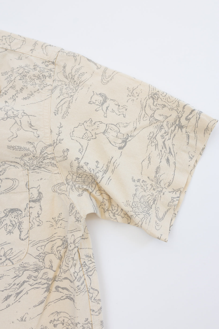 Close-up front view of cream shirt with detailed animal print, short sleeves, and chest pocket