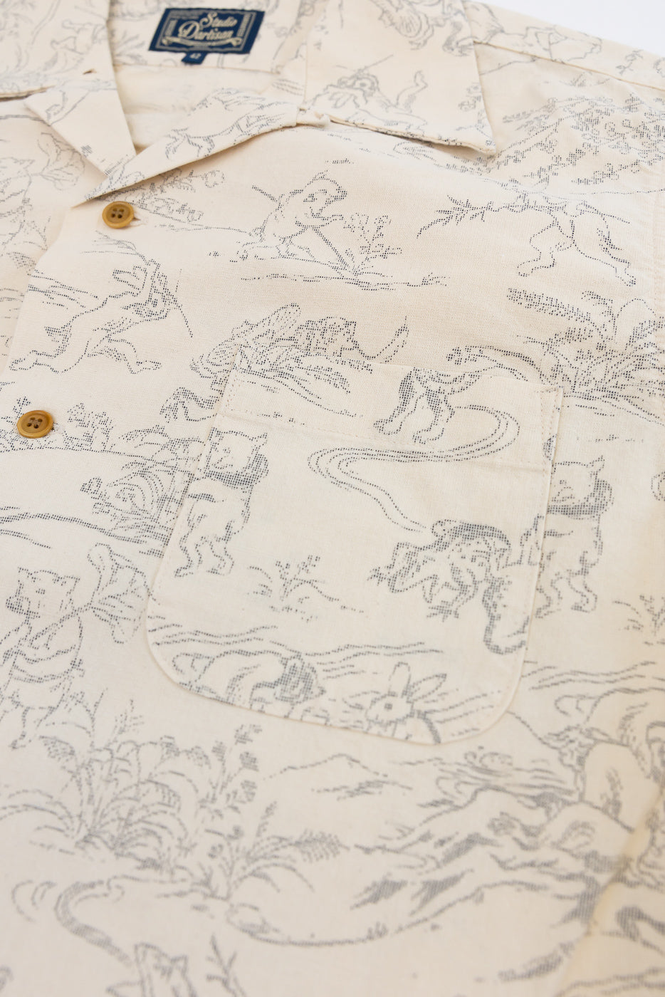 Close-up front view of cream shirt with animal print, button details, and chest pocket