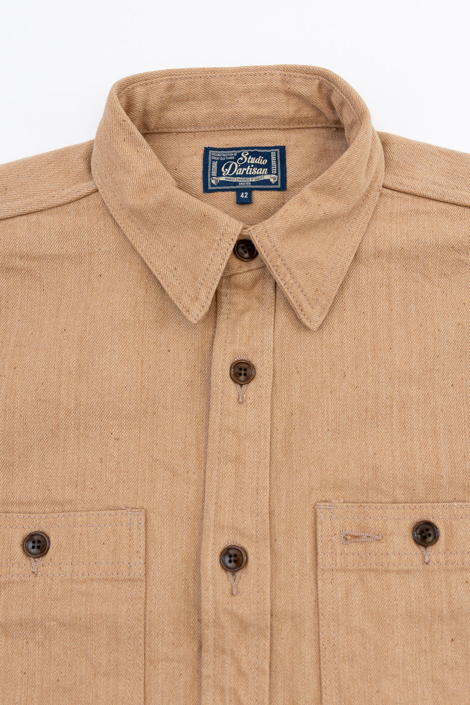 Close-up front view of tan work shirt: collar, button placket, chest pockets, Studio Dartisan label, size 42