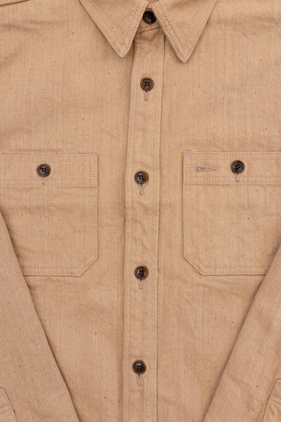 Close-up front view of tan work shirt: button-down collar, chest pockets, dark buttons, textured fabric