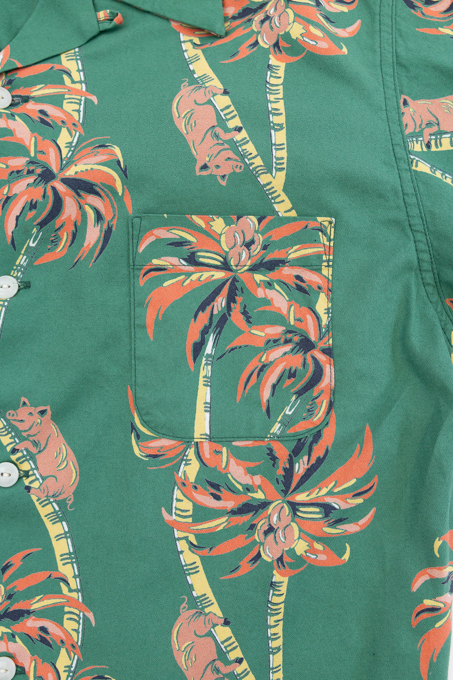 Close-up front view of green shirt with palm tree & pig print, button placket, chest pocket