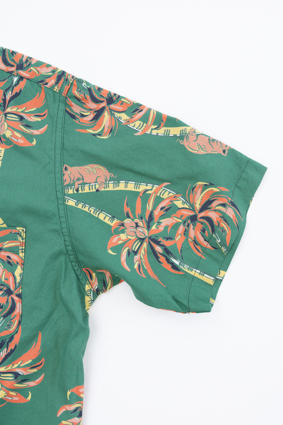 Close-up front view of green tropical print shirt with palm trees, showing sleeve hem and chest pocket detail
