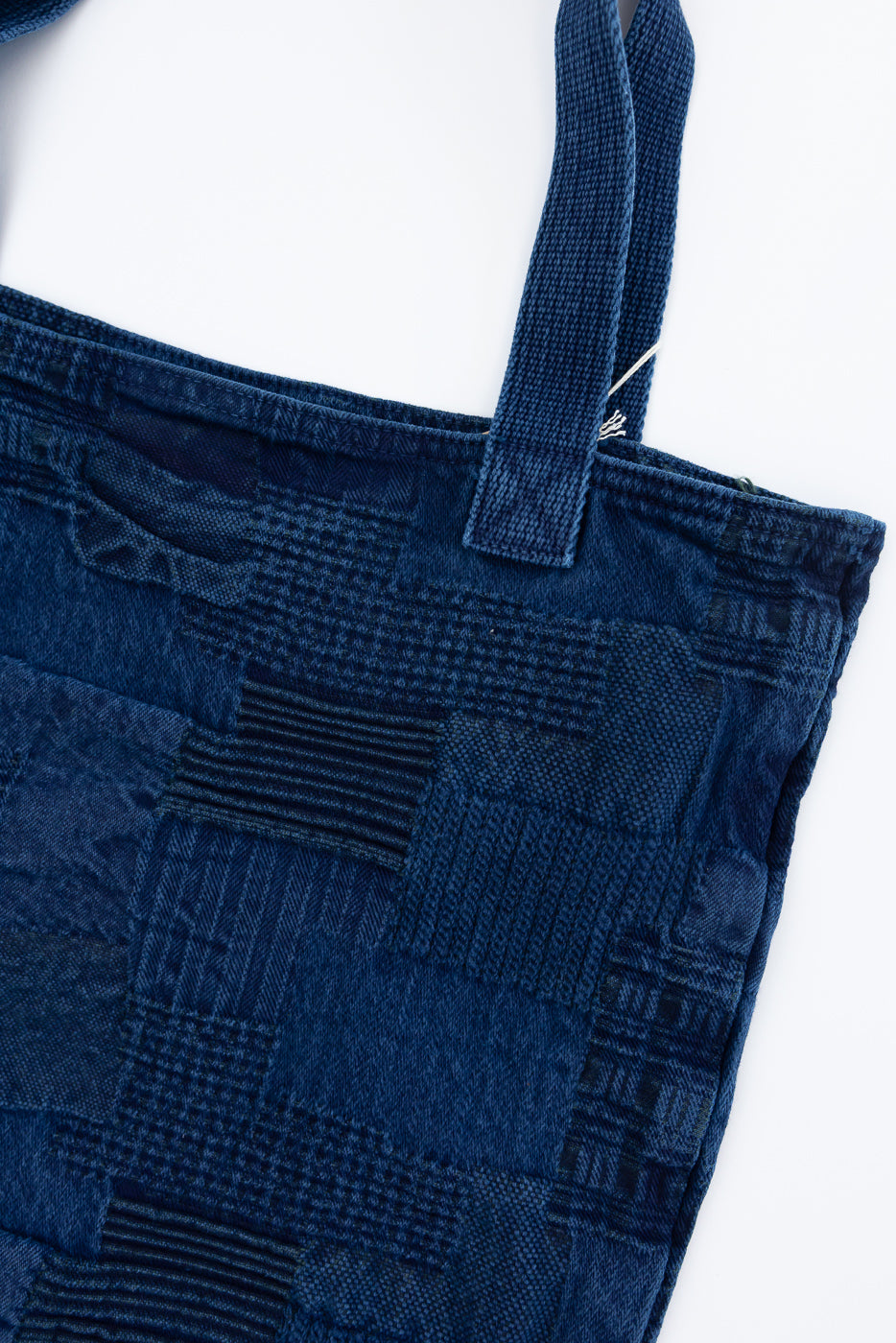 Close-up of front patchwork denim tote bag, showcasing textured fabric and sturdy straps