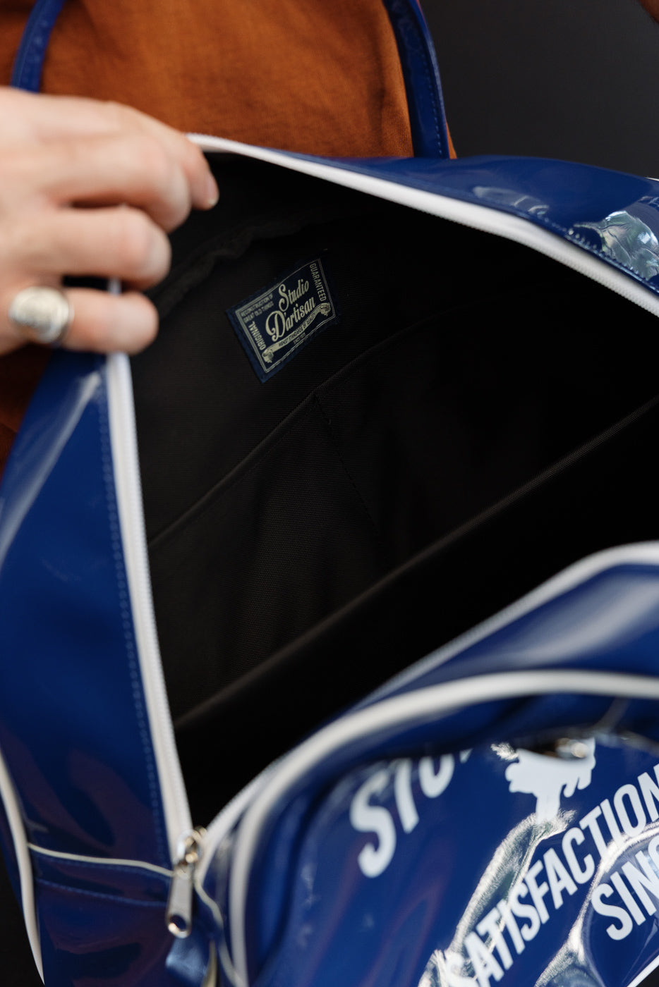 Close-up of blue bag's interior showing Studio Darisan tag, black lining, and white zipper detail.