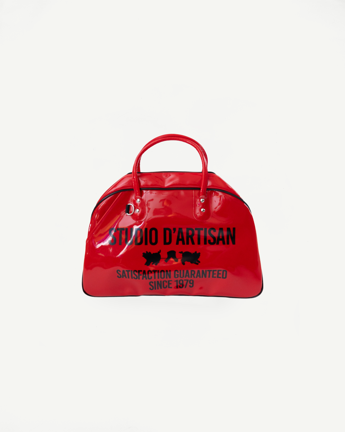 Red glossy duffel bag front view, 'STUDIO D'ARTISAN' print, black trim, handles, and tag details.