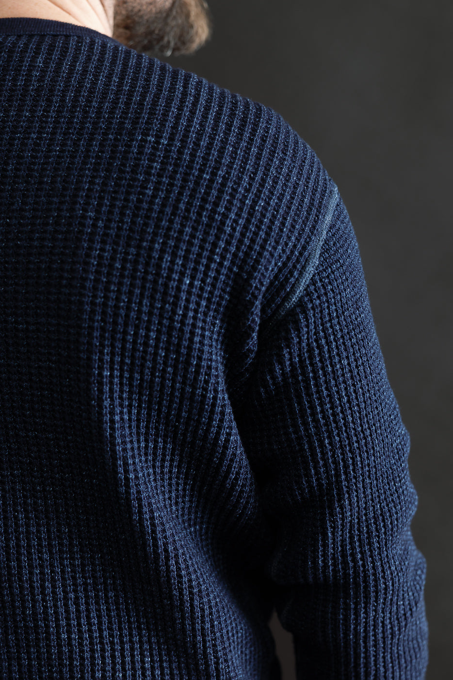 Close-up of indigo-dyed heavy waffle thermal shirt, back left shoulder detail on male model, 5'9