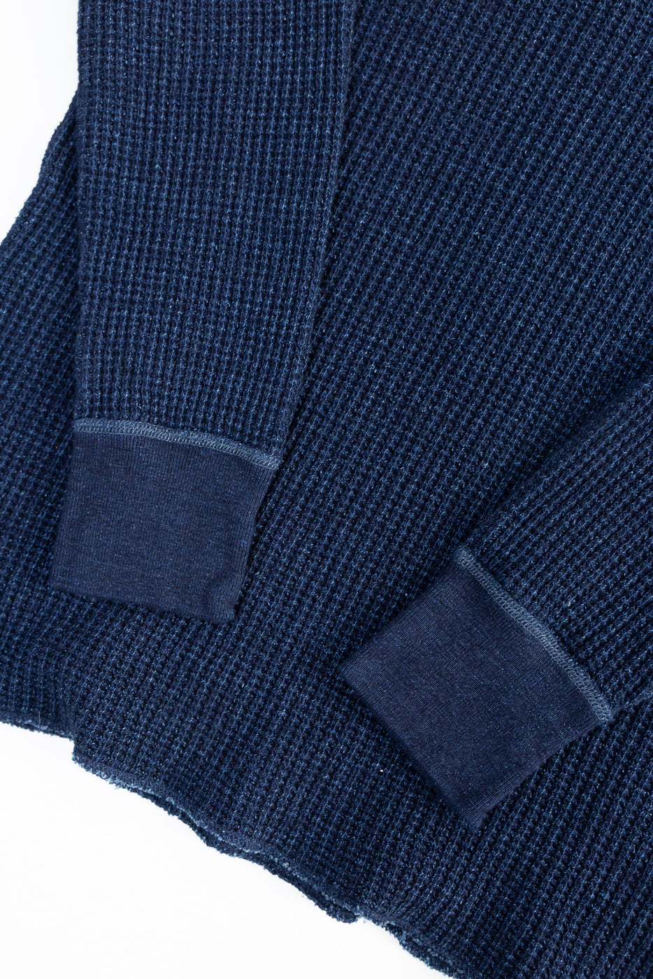 Close-up of indigo-dyed waffle thermal shirt sleeves showing cuff details and fabric texture.