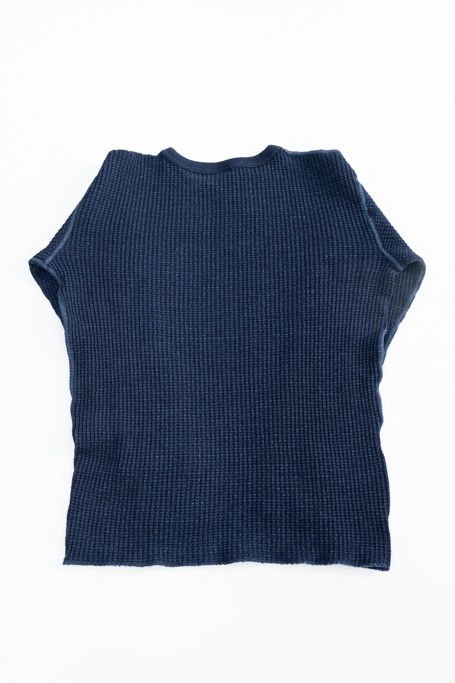 Flat lay of heavy indigo-dyed waffle thermal shirt, back side, showing textured fabric.