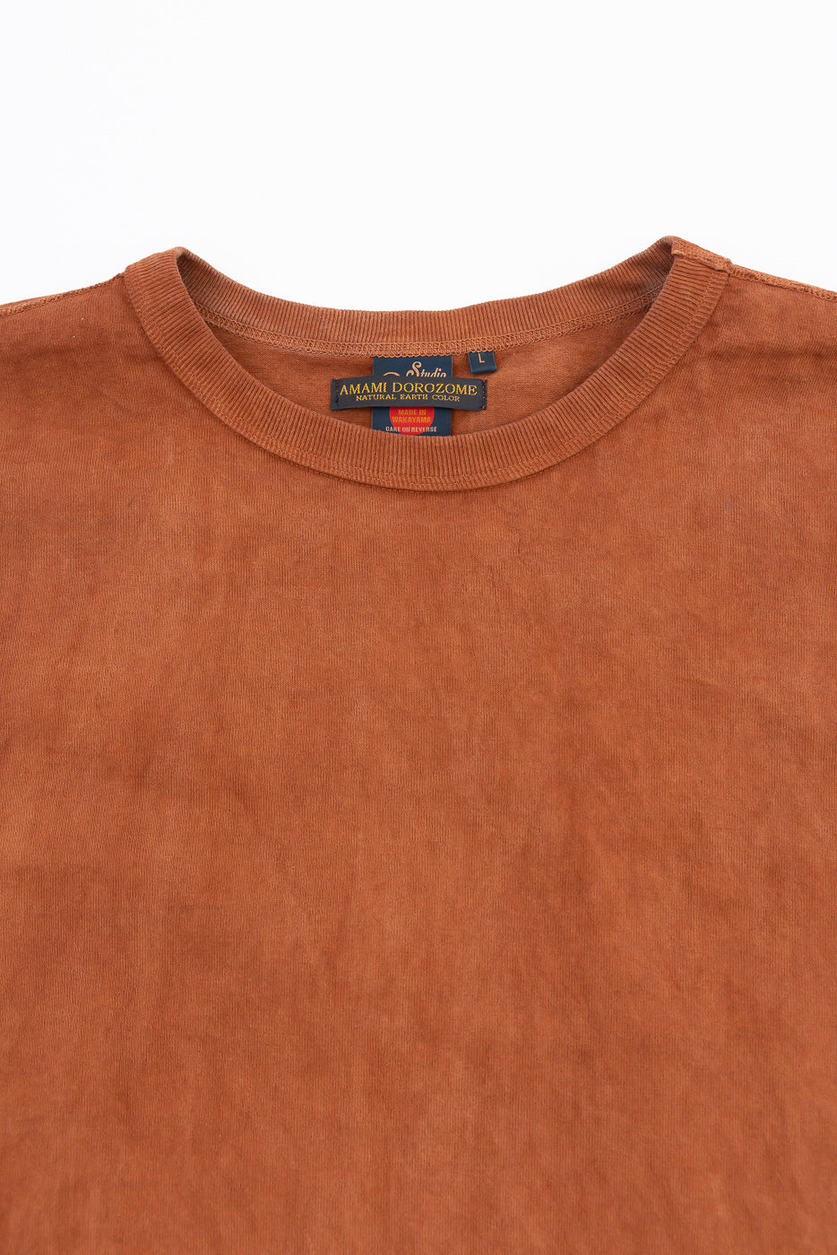 Close-up front view of rust-colored T-shirt collar with tag details, showcasing fabric texture and brand label.