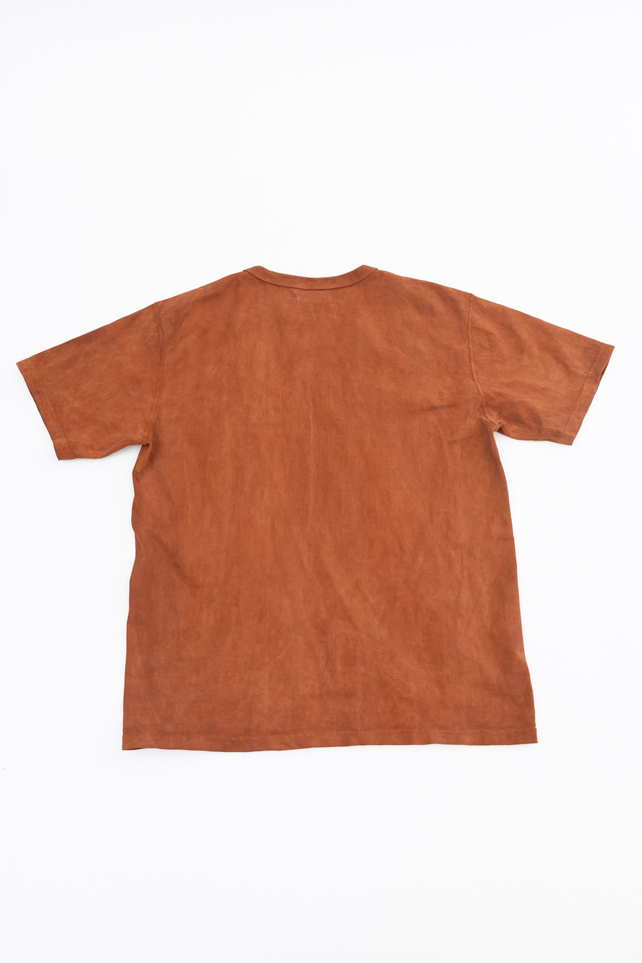 Back view of rust-colored short-sleeve t-shirt, flat lay, showcasing hem and fabric texture