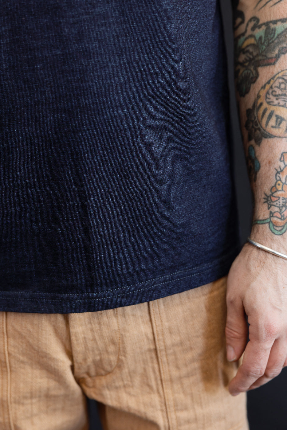 Close-up front view of navy selvedge tee hem on male model, 5'9