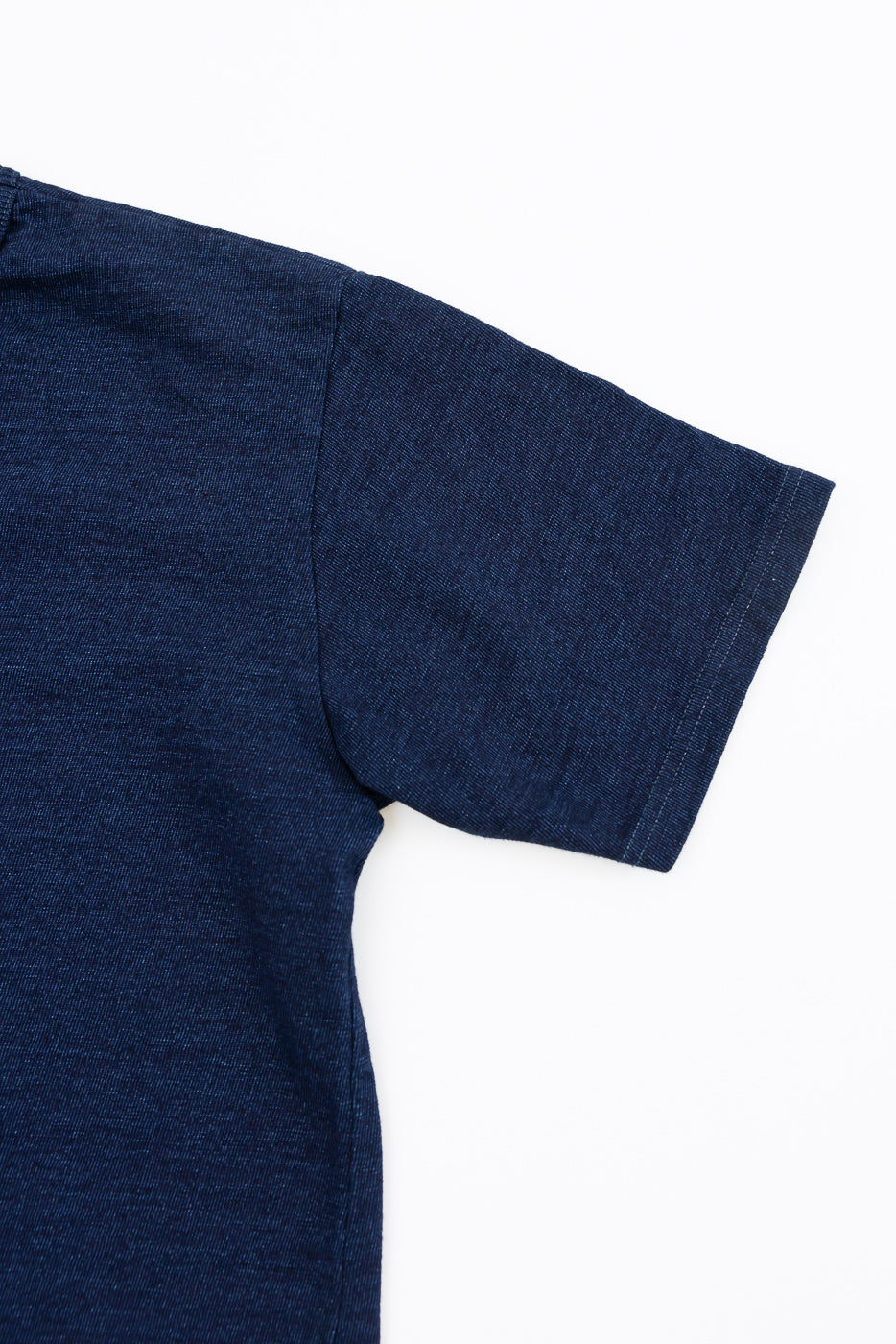 Close-up front view of dark blue short-sleeve tee, showing sleeve hem and textured fabric detail