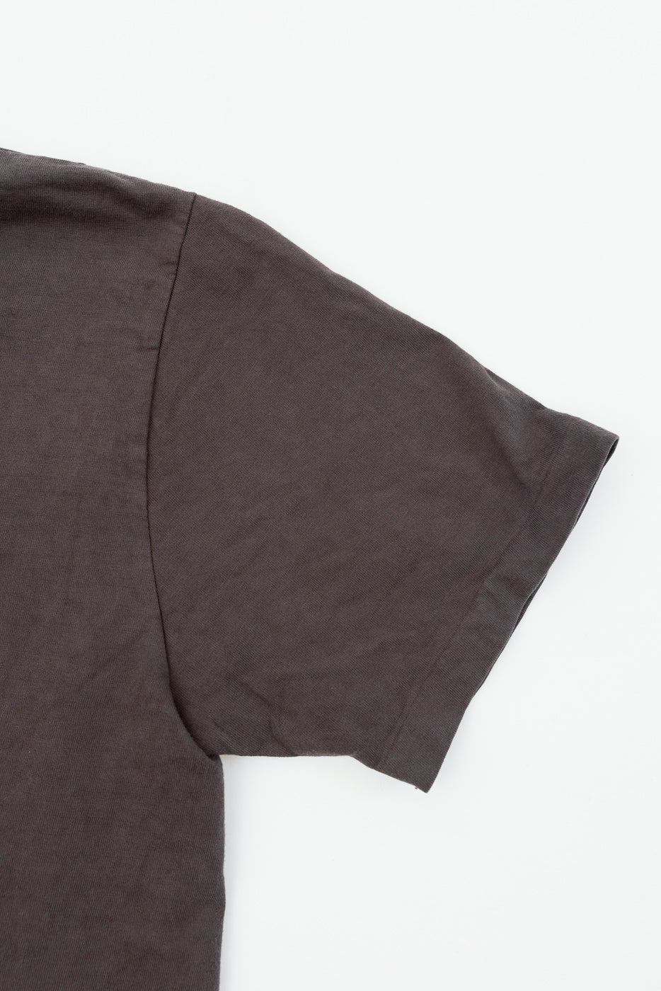 Close-up of dark gray t-shirt sleeve, showcasing fabric texture and hem detail